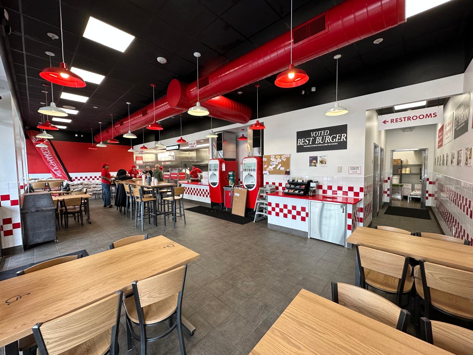 Finished Five Guys restaurant dining room with red pendant lights and checkered tile